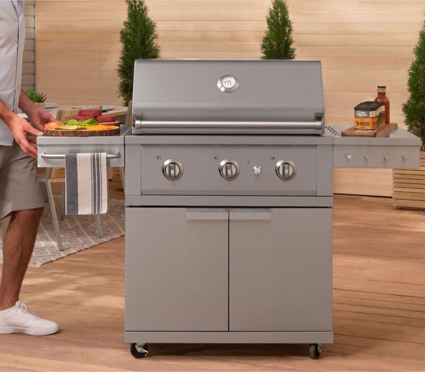 Man pushing silver outdoor grill on patio