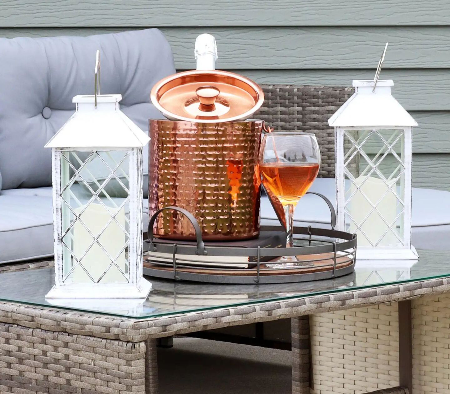 Two white lanterns sitting on top of a glass outdoor table