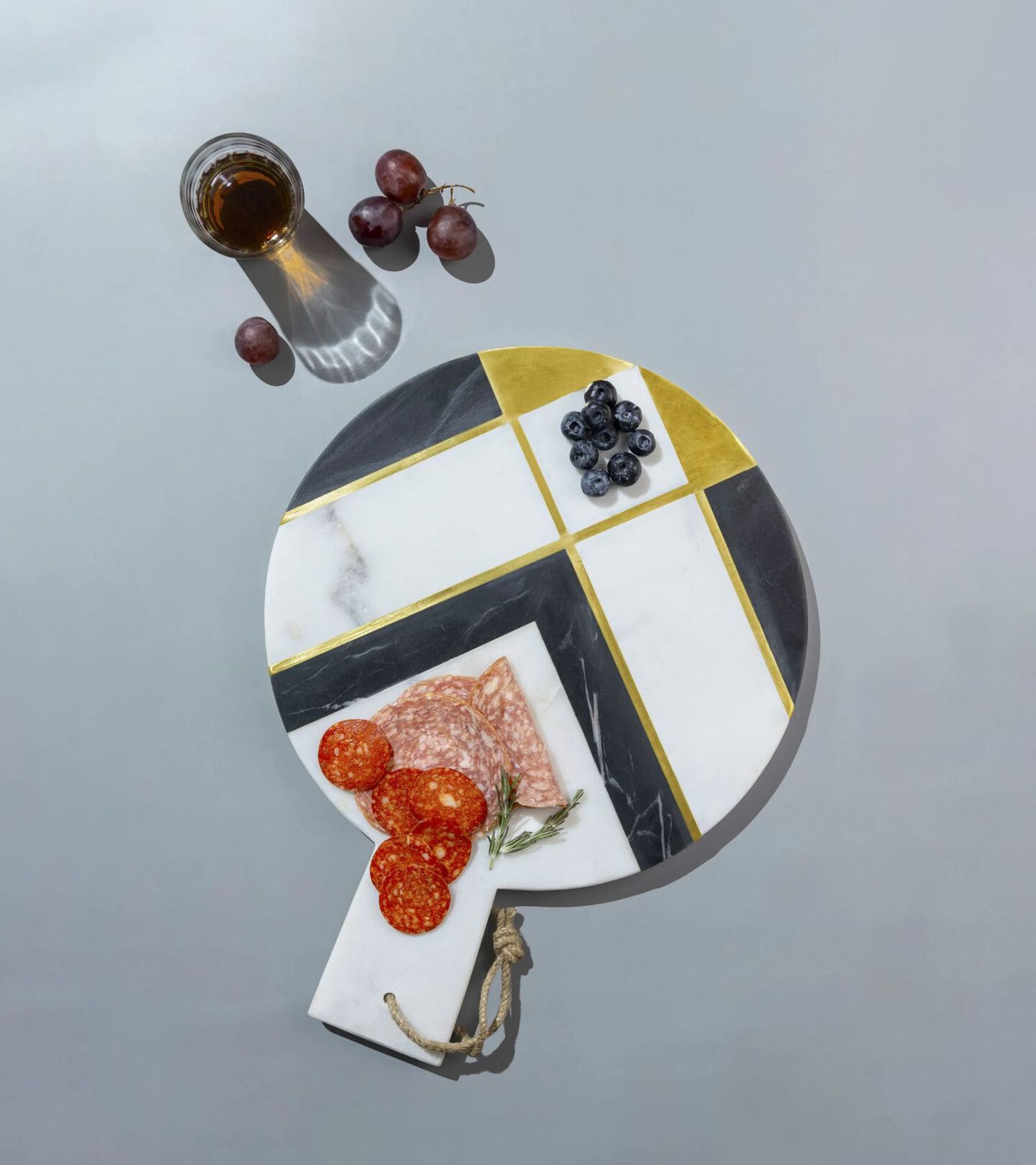black, white and gold marbled cheese board with fruit and meat on top