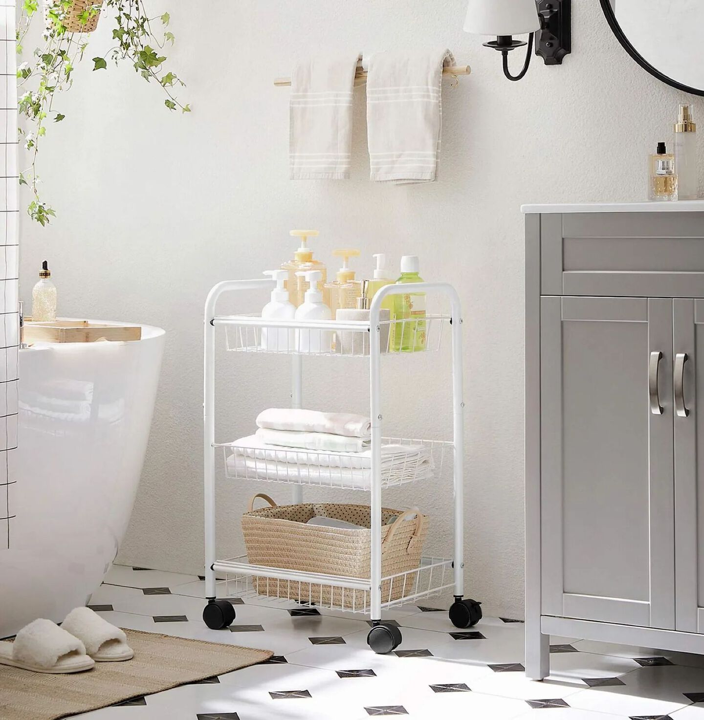 Bathroom with white rolling shelf with bathroom supplies, a white bathtub, and grey sink