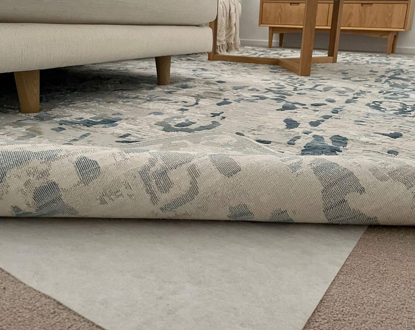 closeup of a rug folded back to show a rug pad underneath
