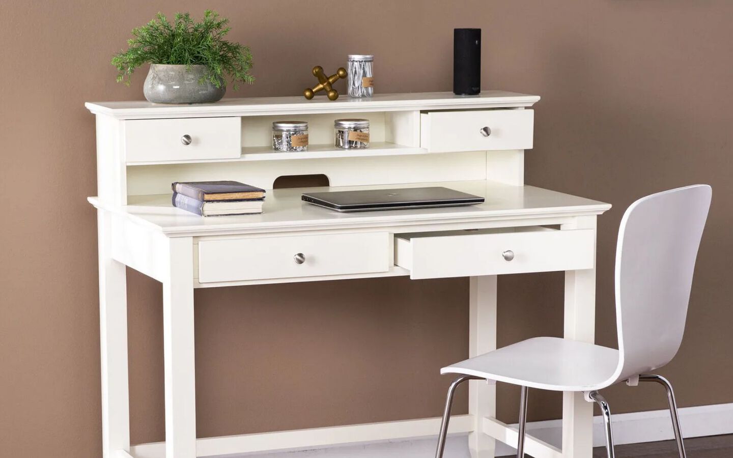 White desk with fake plant, books, other small objects and white desk chair in front