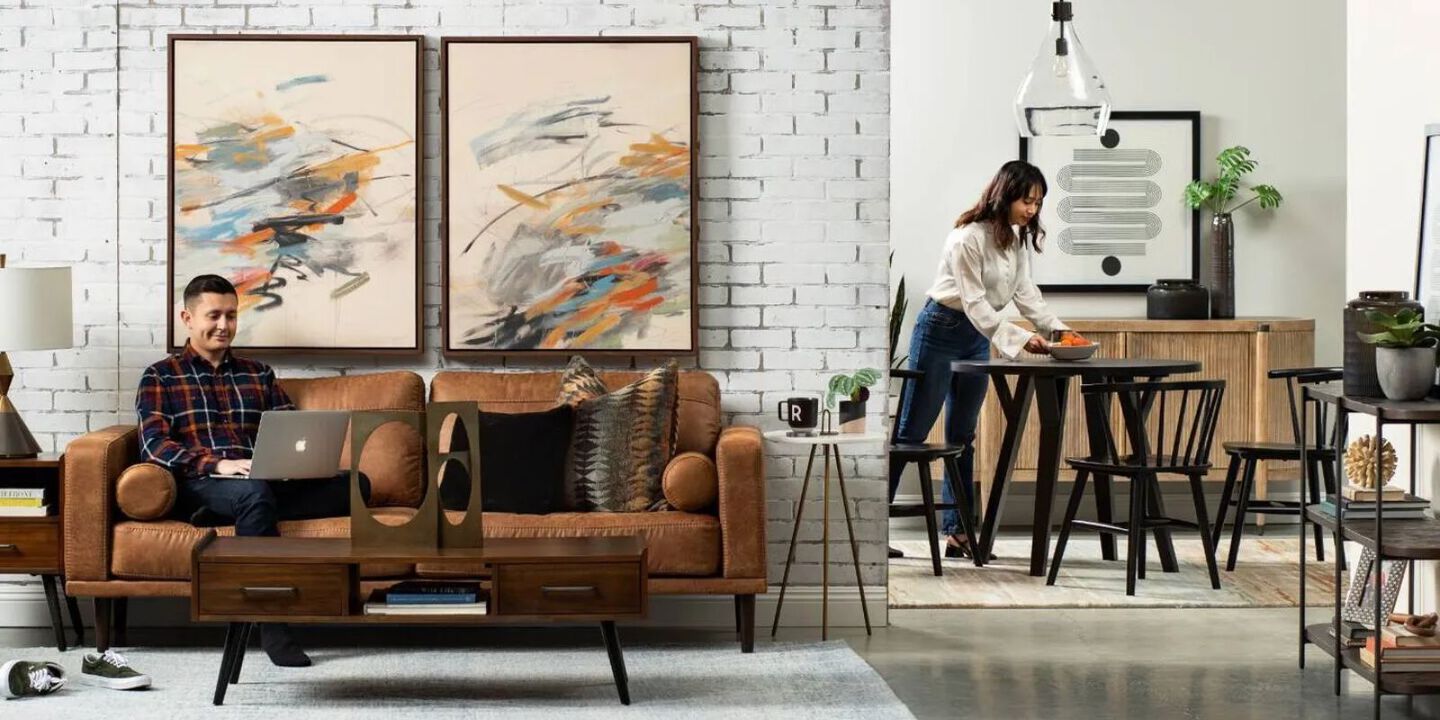 Living room and dining room filled with brown and black furniture divided by a white brick wall