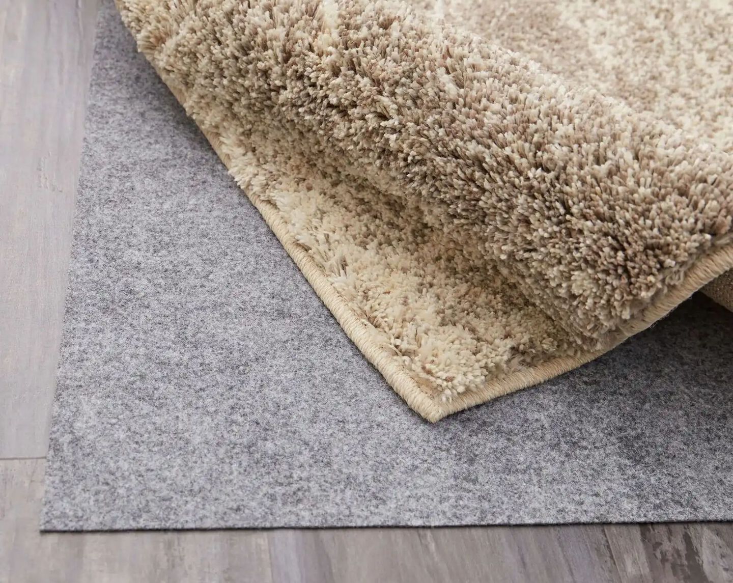 closeup of a shag rug scrunched up to show a rug pad underneath