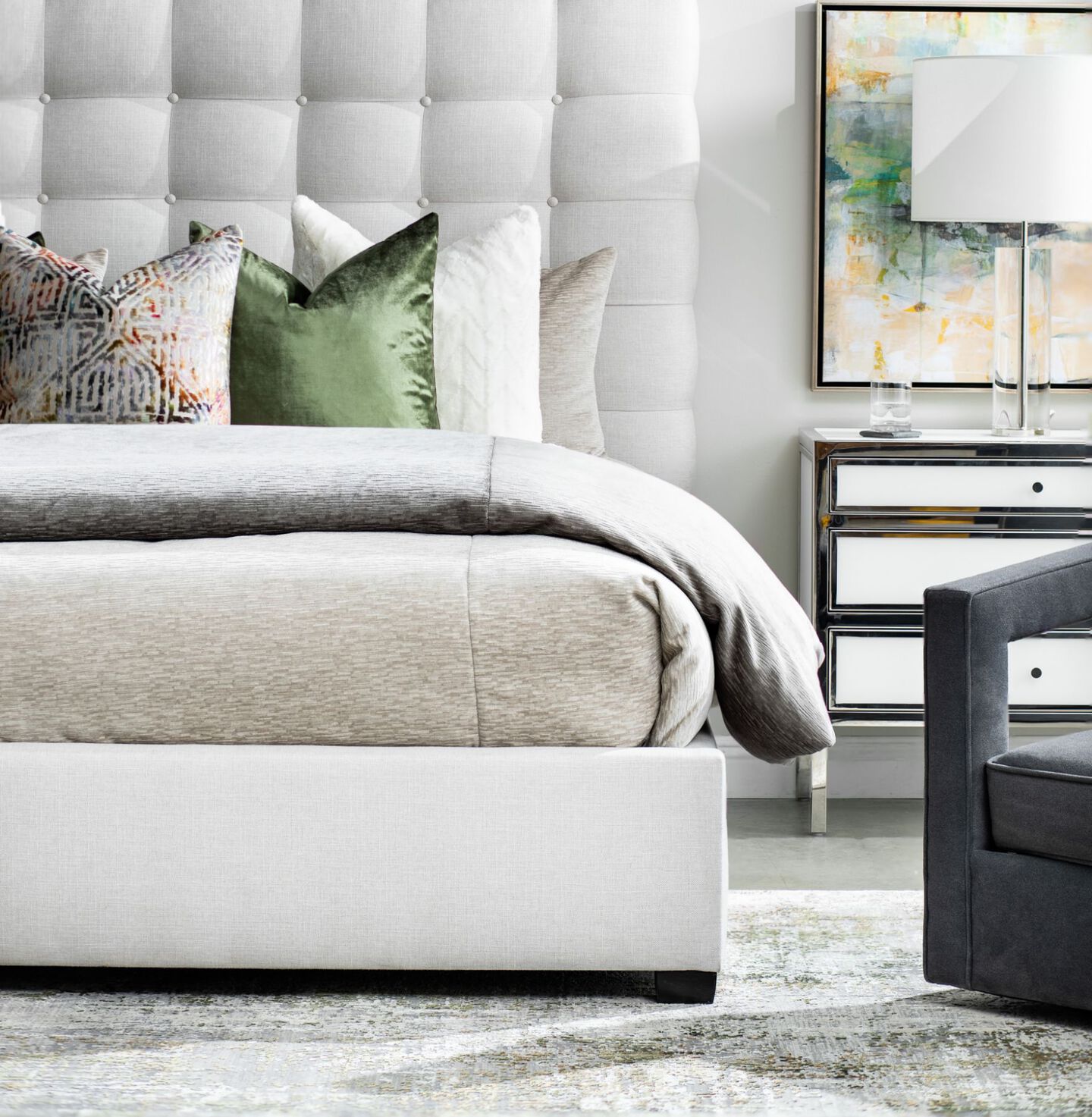 Bed with light gray headboard and baseboard, silver bedding, and green, white, and beige pillows