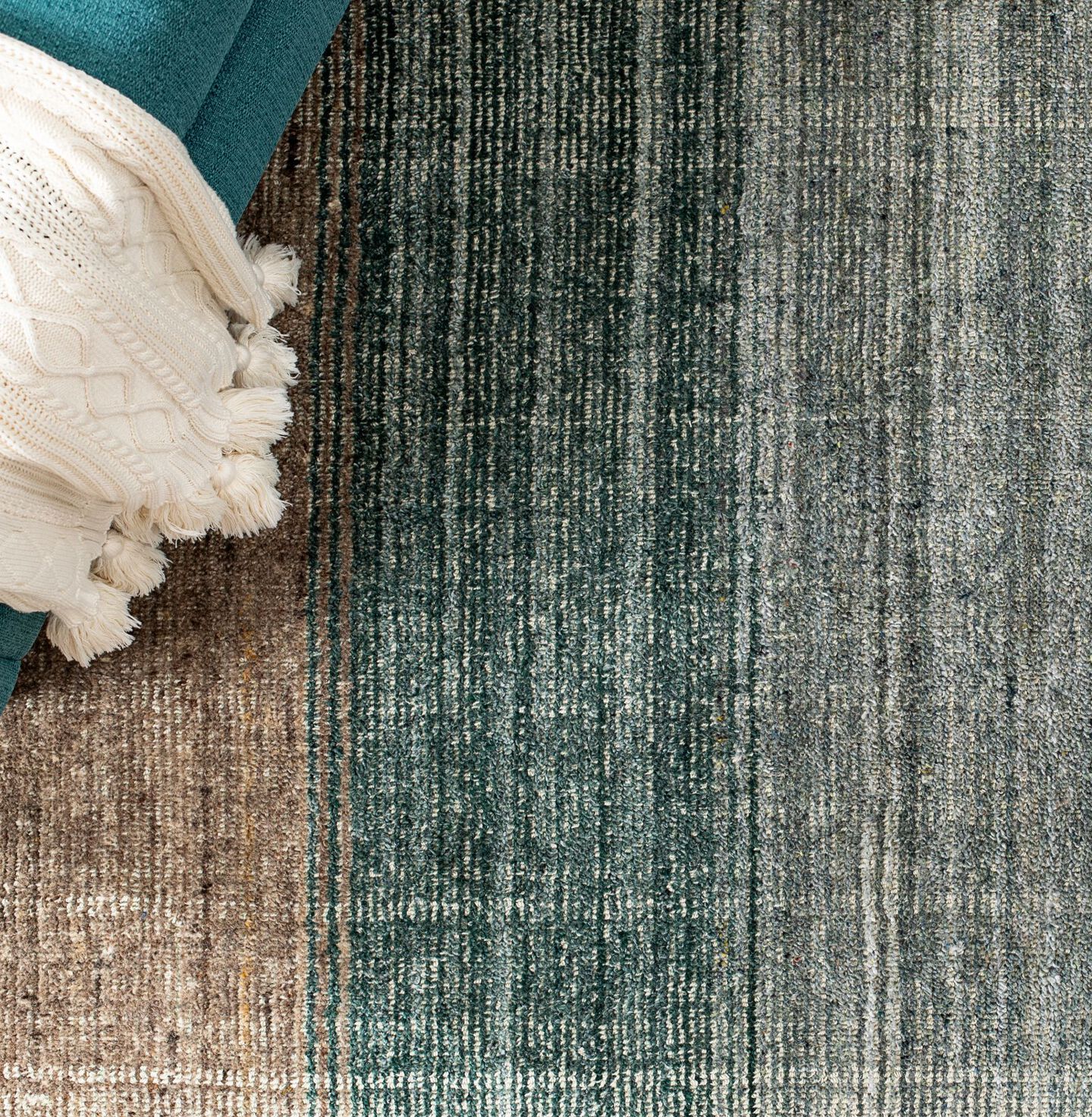 Aerial view of a blue and beige textured rug with a teal chair sitting on top of it