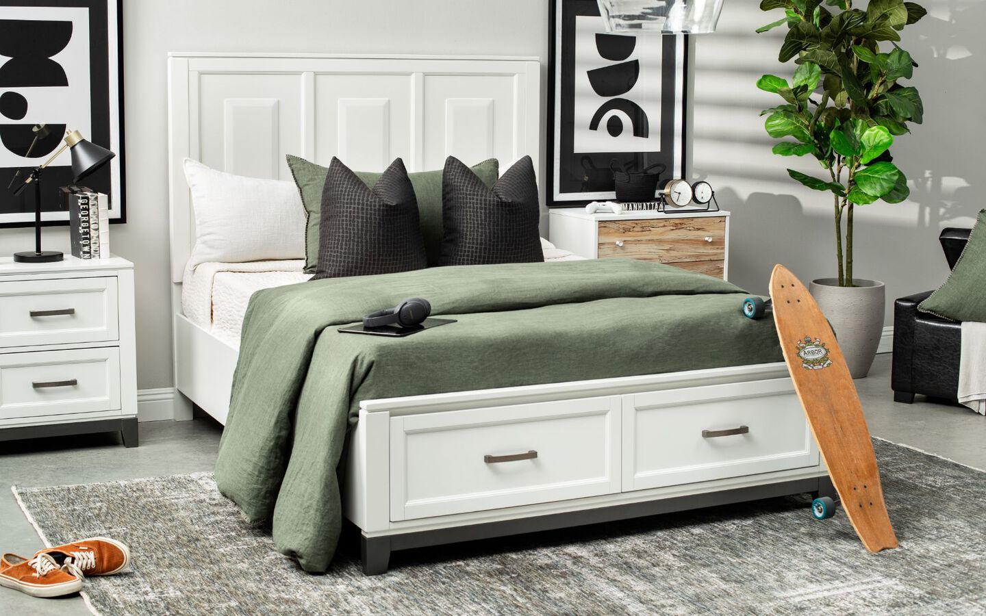 Bedroom with white bedframe with green comforter, black pillows, and matching white nightstand