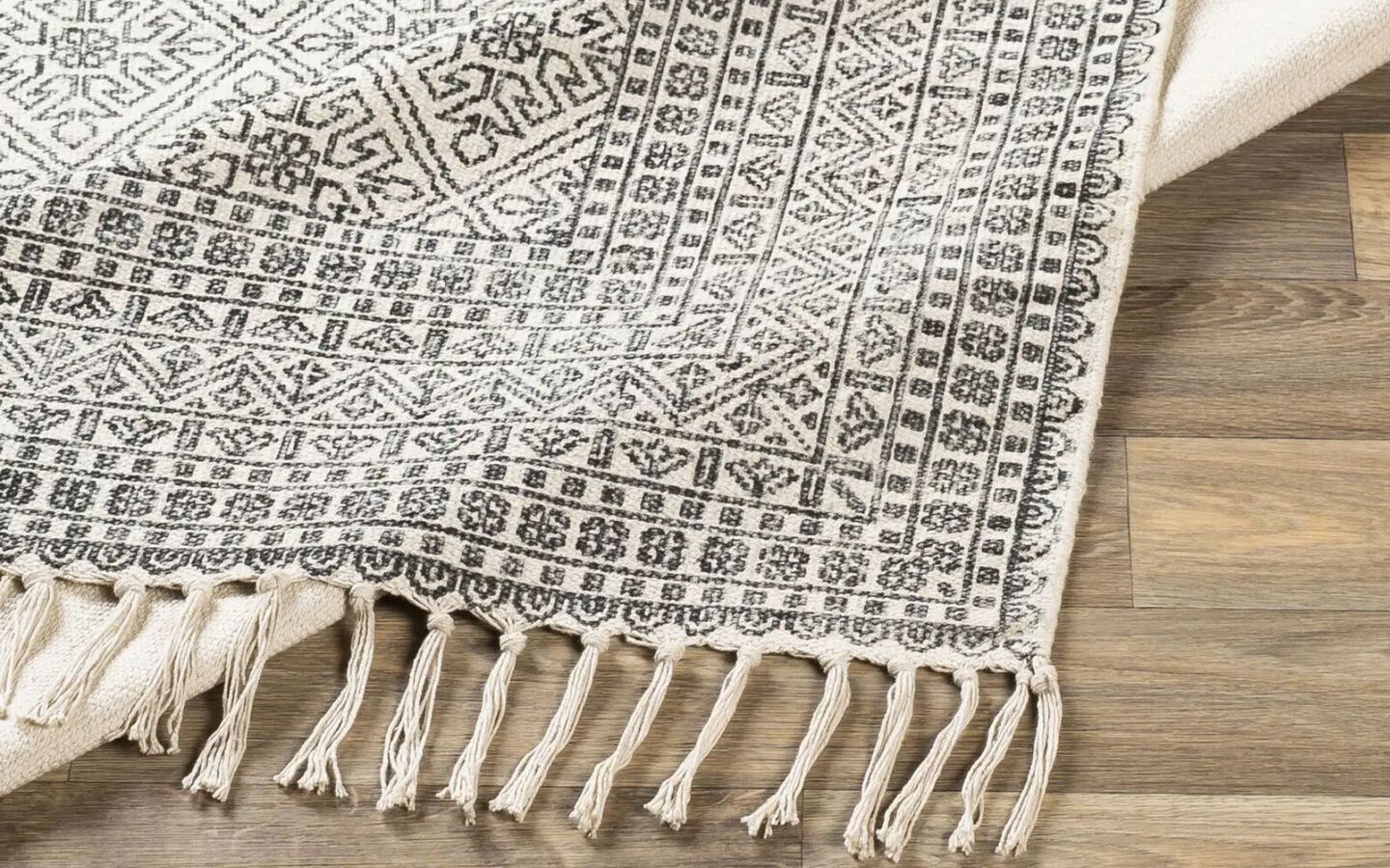 closeup image of a black and white rug with knotted edges