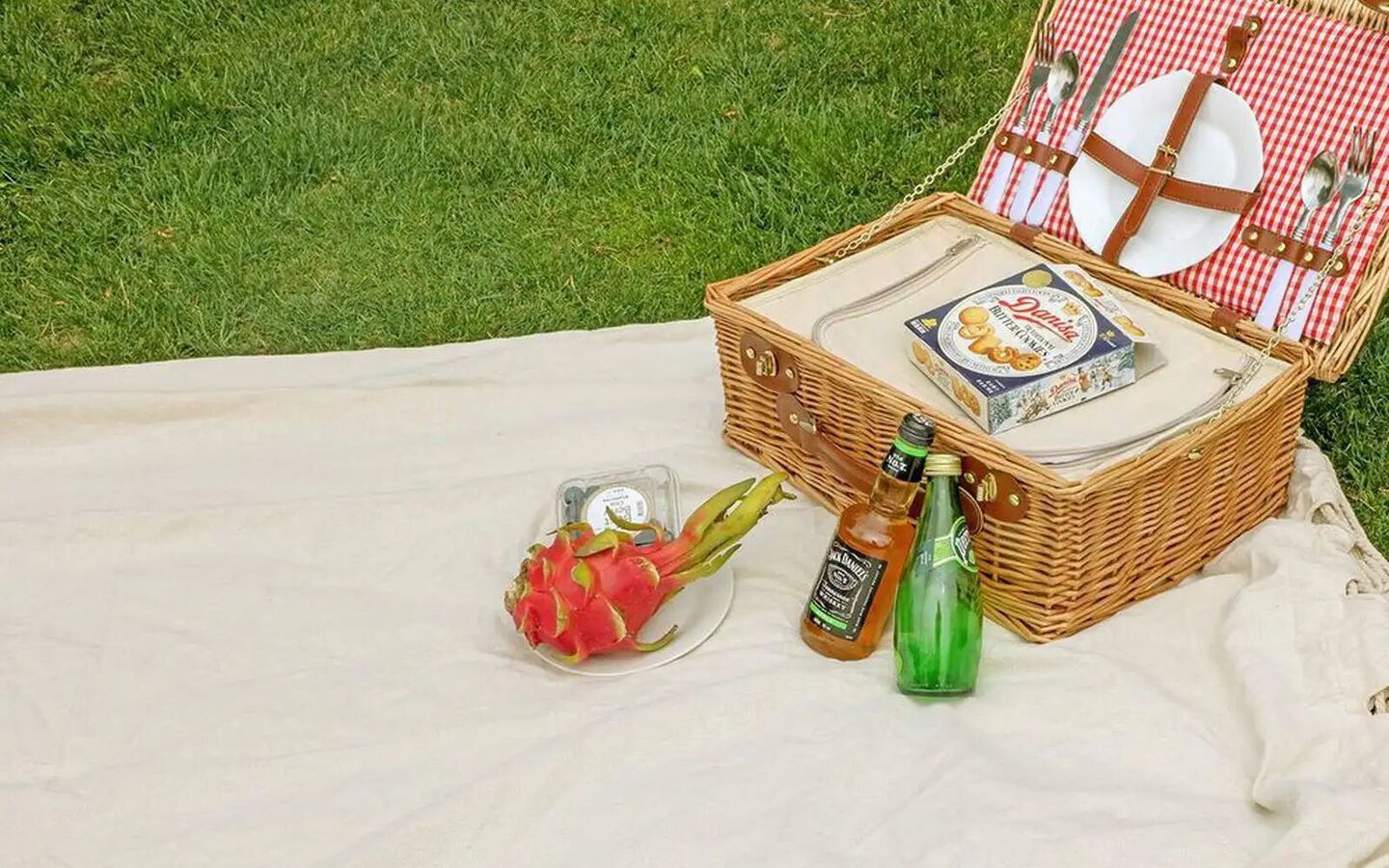 Hammock laying flat in the grass with a picnic basket with food and drinks sitting on top