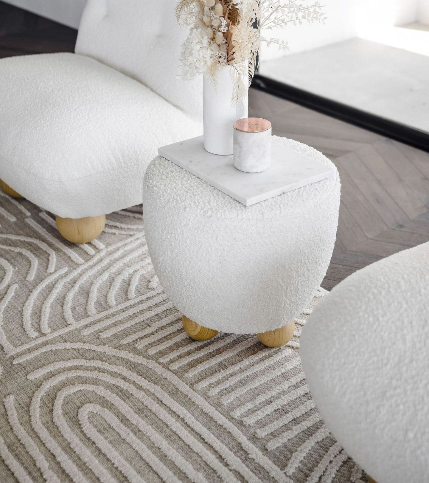 white plush stool and chairs atop a beige and white patterned rug