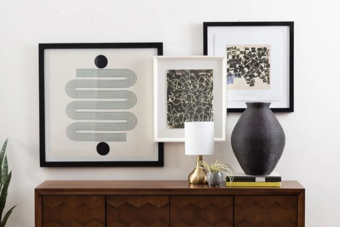 Wall with three picture frames hanging above a wooden table