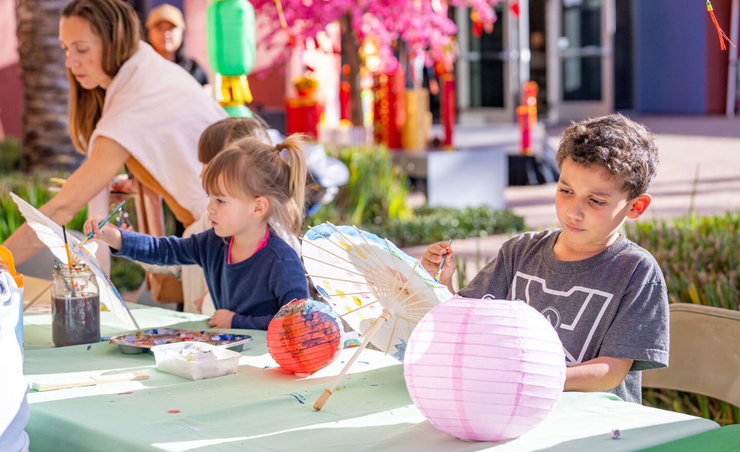 Several children painting and decorating paper umbrellas and lanterns