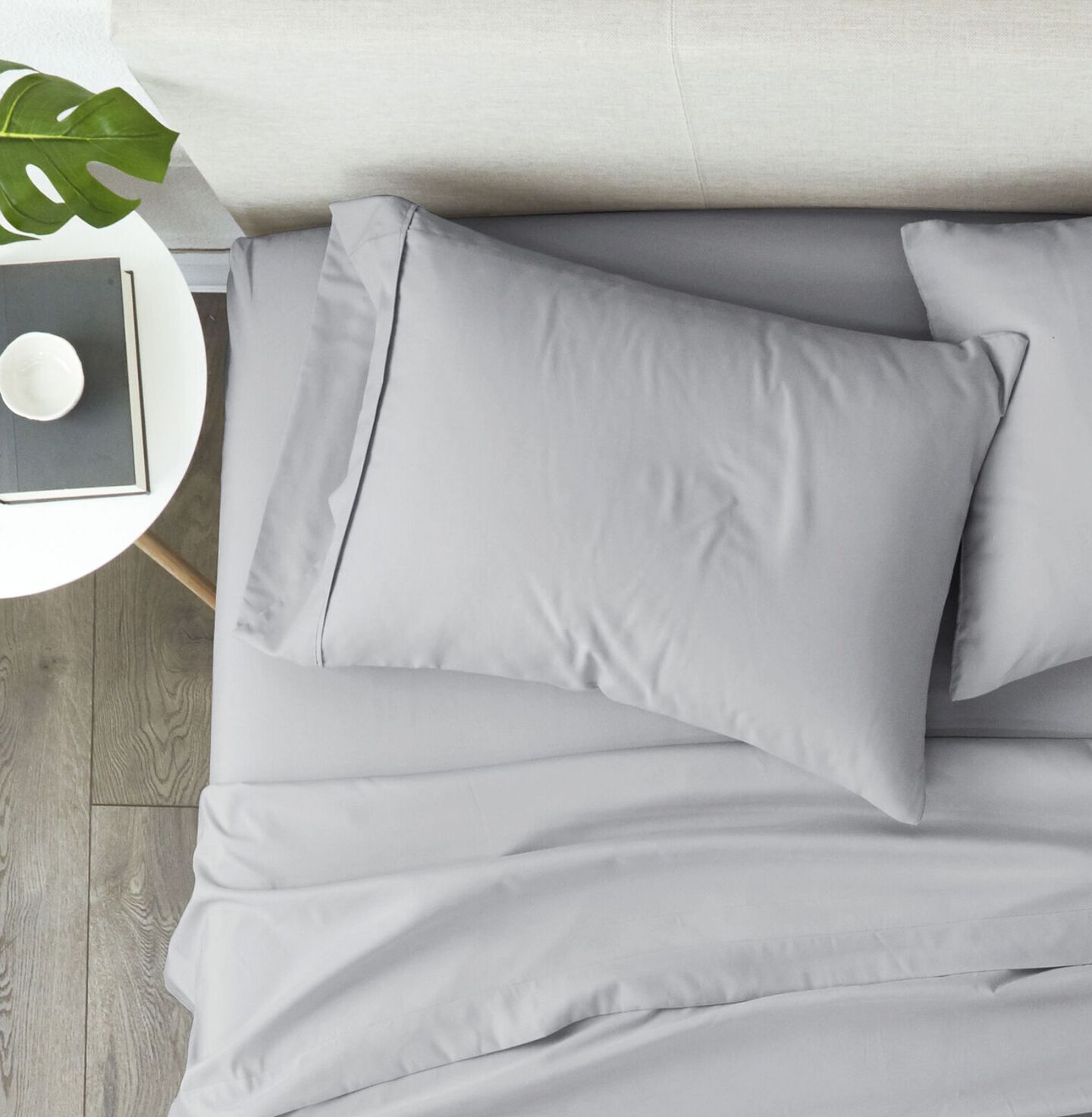 Aerial view of a bed with a beige bedframe made with light-grey sheets
