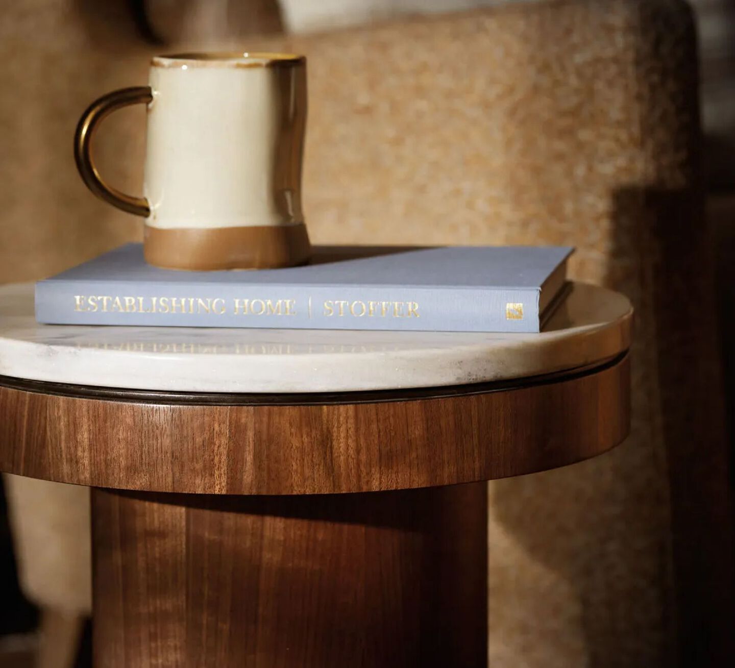 Wooden coffee table with a white stone top and a book and mug sitting on top