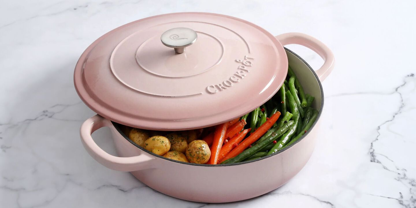 Marble counter with a pink ceramic cooking dish filled with veggies on top