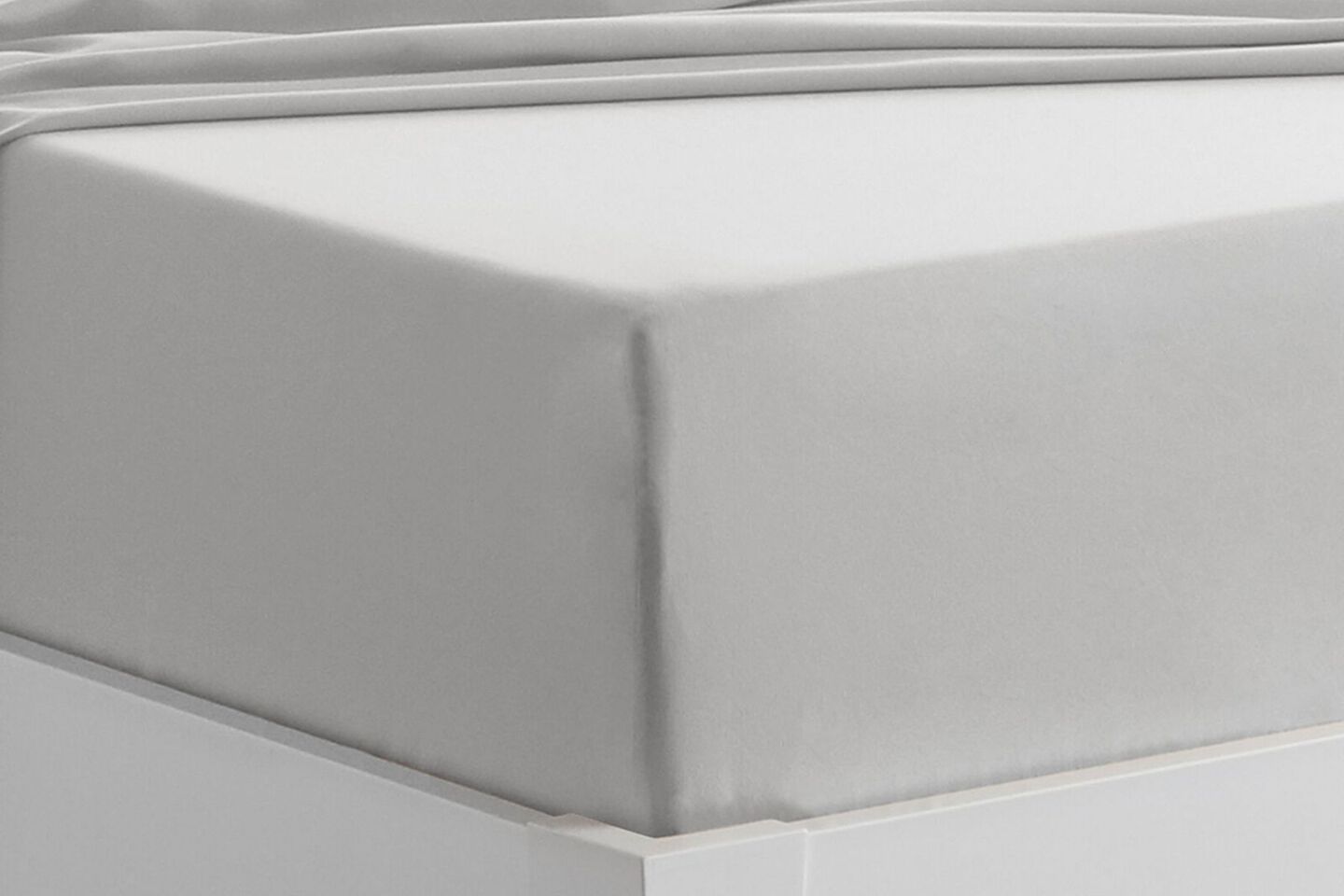 Close up of the corner of a tightly made bed with grey sheets