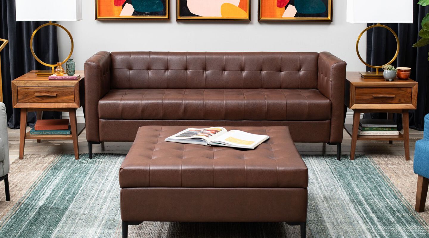 Living room with two brown side tables and a dark brown couch and ottoman on a blue rug