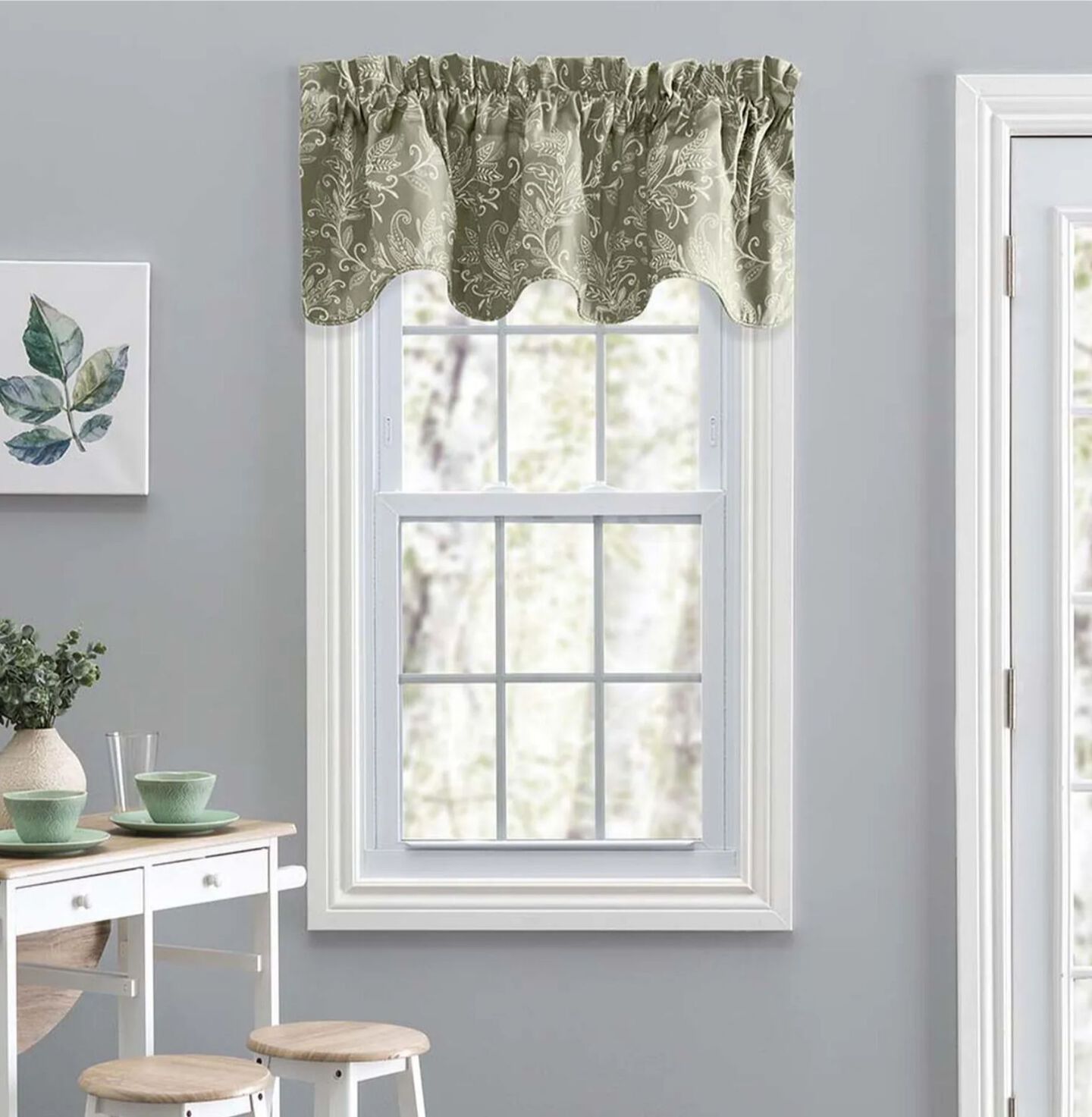 White paneled window with short green patterned curtains