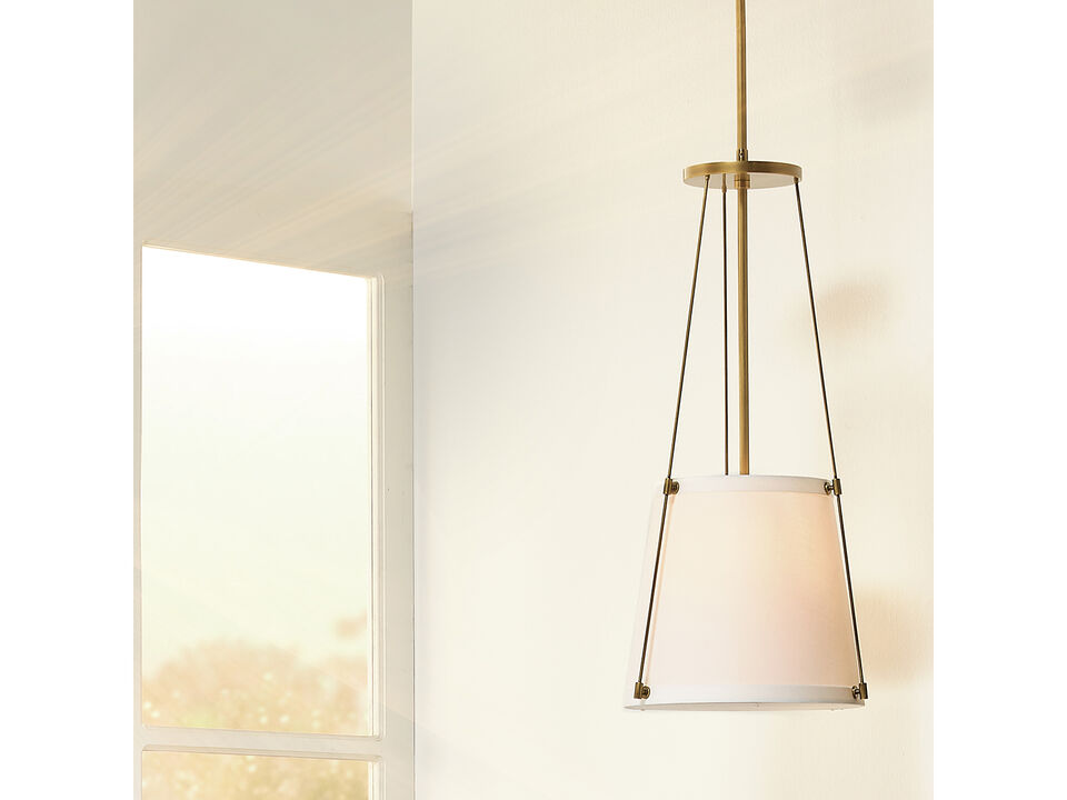 Hanging pendant light with an off-white drum shade and antique brass framework